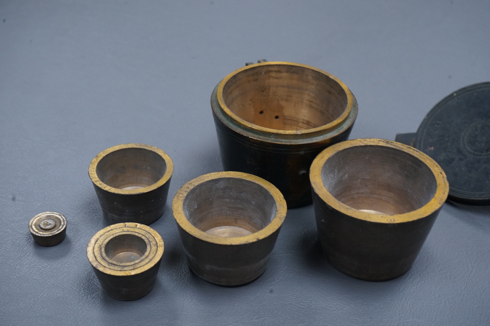 A 19th century brass nest of weights, the case with engraved inscription, 18 stone/4lb, Weeks’s Mechl. Museum, Tichborne St., 10cm wide
